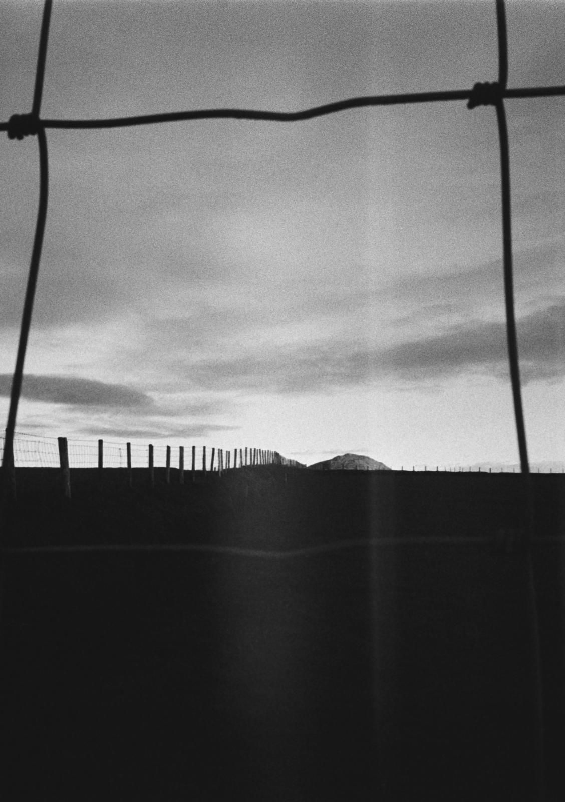 A hill seen through a fence